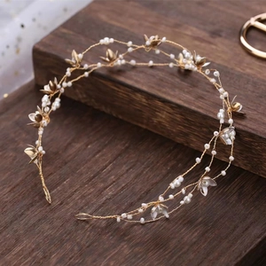 Detail of gold flower bridal headband with white pearls on a rustic wood background