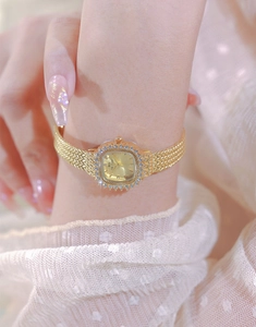 Close-up of elegant gold square watch with crystal bezel and Milanese mesh strap