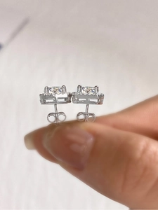 Detailed view of square cut moissanite stud earrings in a classic silver halo setting
