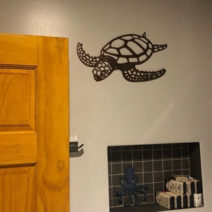Minimalist sea turtle metal wall art decoration displayed in a modern living room setting