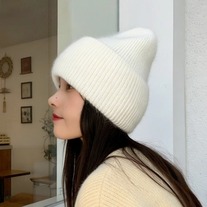 Close-up of thick knitted beanie in cream white with soft plush rabbit hair texture