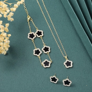 Elegant gold five-petal flower jewelry set with necklace and earrings on green backdrop