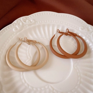 Retro geometric hoop earrings in matte beige and brick red on a ceramic tray