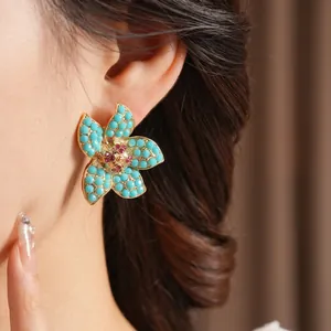 Vintage floral stud earrings with blue beads and magenta crystals on a golden base
