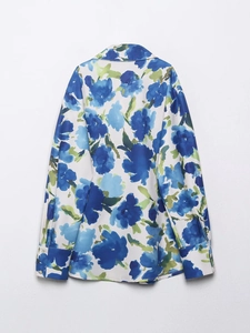 Détail de l'imprimé floral bleu sur une chemise en satin de soie à manches longues