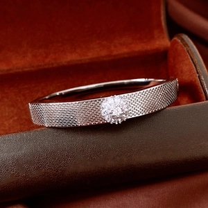 Detail of silver floral bangle with zircon cluster and woven texture on jewelry box