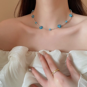 Détail du collier de perles avec fleurs bleues et perles argentées sur le mannequin