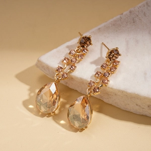 Detail of drop-shaped amber stones on gold necklace and earrings set with crystal accents