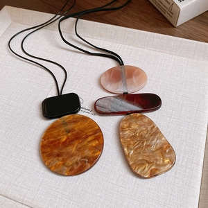 Detailed macro shot of geometric resin pendant necklaces with artistic marble patterns