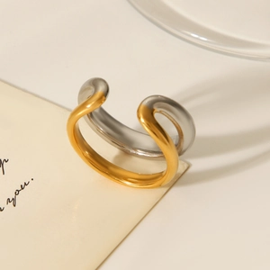 Detailed shot of two-tone gold and silver wave ring on minimalist beige surface