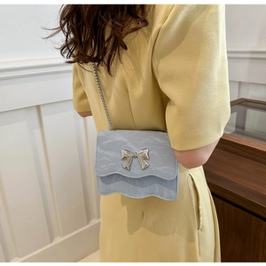 Gros plan d'un sac bandoulière bleu clair texturé avec une boucle de nœud argentée