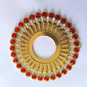 Detailed close-up of golden metal round wall decor featuring red gemstone accents
