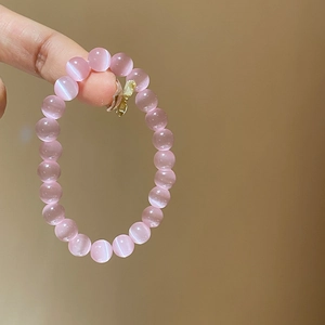 Detailed macro view of 8mm pink cat eye stone beads on a delicate beaded bracelet