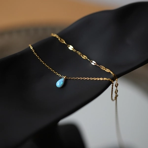 Gros plan du collier goutte d'or avec opale bleue miroitante sur support noir