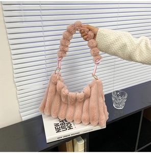 Close-up of pink plush handbag featuring rippled texture and fluffy ball handle detail