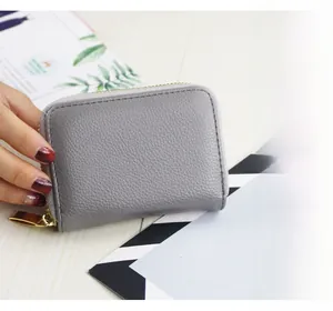 Close-up of a grey litchi texture leather card holder with a gold wrap-around zipper