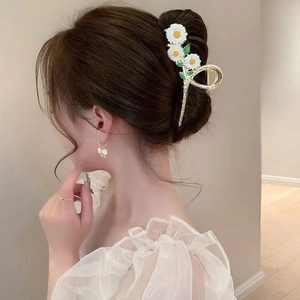Detail of floral daisy hair claw clip with white enamel petals on elegant female model