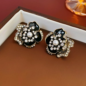 Macro shot of vintage style flower earrings with black enamel and sparkling rhinestones