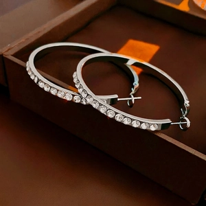 Close-up of large silver hoop earrings with clear zircons on a luxury leather box