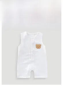 Detail of white cotton gauze baby romper with plush bear patch and snap closures