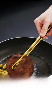 Vue macro d'une pince à grillade en acier inoxydable doré retournant de la viande