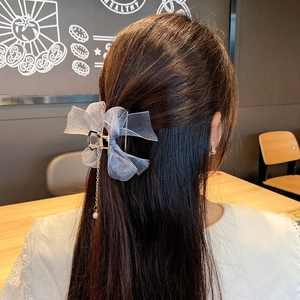 Detail of mesh bow hair claw with elegant pearl tassel pendant in a natural setting