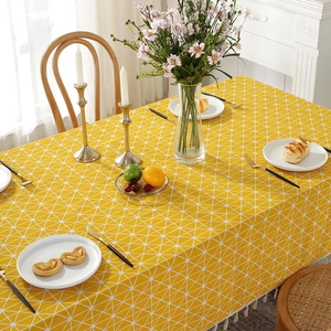 Detail of yellow cotton linen tablecloth with white geometric pattern and tassels
