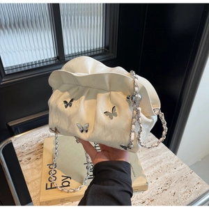 Detailed view of white pleated bucket bag with silver butterfly charms and chain strap