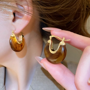 Détail de boucles d'oreilles vintage en résine ambrée et métal doré en forme d'U