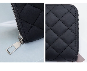 Close-up of quilted black leather wallet featuring silver zipper and detailed stitching