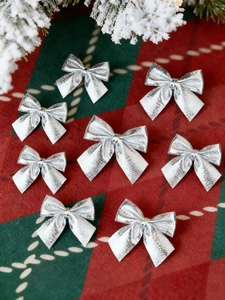 Close-up of metallic silver Christmas tree bows on festive red and green plaid background