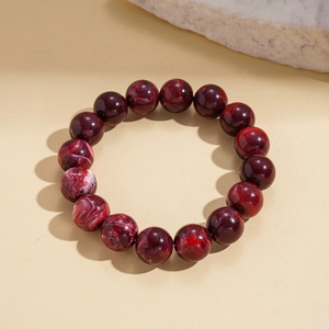 Detailed shot of red marble pattern acrylic beads bracelet on warm textured surface