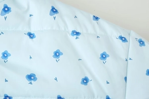 Detail of light blue floral print fabric with horizontal quilted texture for puffer jacket