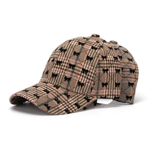 Close-up of brown plaid baseball cap featuring black bow embroidery and stiff brim