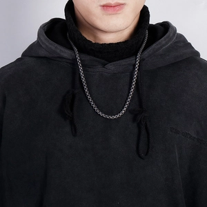 Close-up of a silver dragon bone steel chain necklace worn by a male model on a grey hoodie
