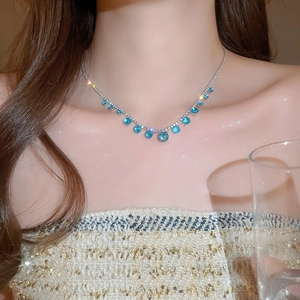 Macro shot of silver necklace with dangling blue zircon charms worn by a model
