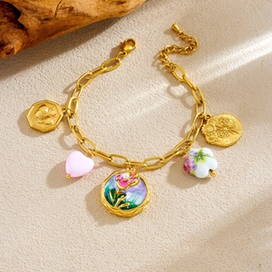 Vintage gold charm bracelet with flower enamel pendants and heart beads on wood base