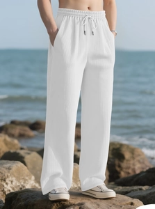 Detailed view of white pleated wide-leg pants featuring vertical texture and drawstring waist