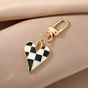 Detail of a heart-shaped keychain with black and white checkerboard pattern and gold hardware