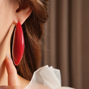 Gros plan d'une boucle d'oreille goutte en résine rouge portée par un mannequin