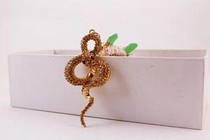 Close-up of golden snake keychain with sparkling brown rhinestones on a white box