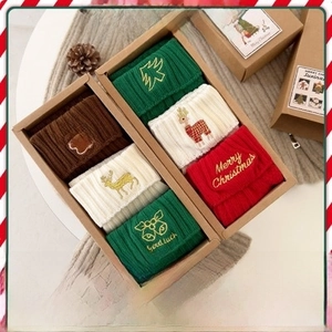 Three pairs of knit Christmas socks with festive embroidery in a kraft gift box