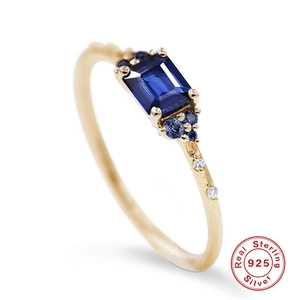 Macro detail of gold sterling silver ring with rectangular blue gem and side stones