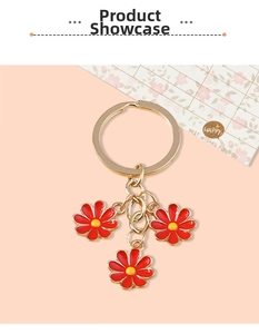 Detail view of gold metal keychain with three red and yellow daisy enamel charms