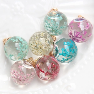 Detailed close-up of spherical resin pendants with colorful dried flowers and gold loops