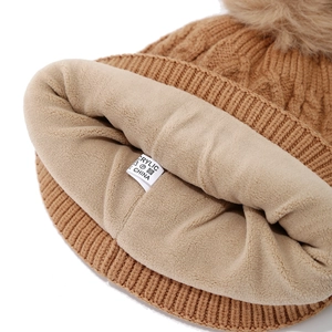 Close-up of brown knit hat showing warm fleece lining and acrylic material label