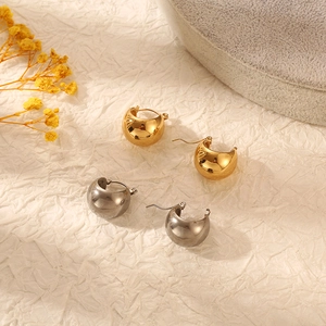 Detailed view of wide curved hoop earrings in polished gold and silver finishes