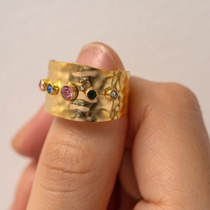 Macro view of wide 18K gold stainless steel ring with hammered texture and colorful gems