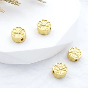 Vue macro de 4 perles fleurs dorées aux pétales en cœur pour la création de bijoux DIY