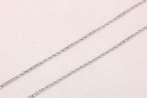 Macro shot of fine silver-toned stainless steel cross chain link on soft pink surface